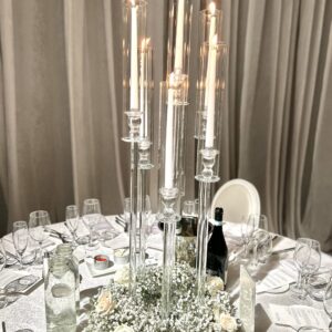 Clear 7 head candelabras with candles and white roses and baby's breath at the base on guest table for wedding reception